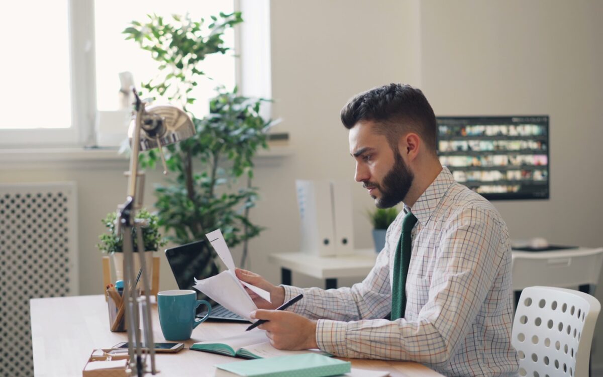 Man sitting at a desk with a laptop and papers, summarizing a long PDF report using AI