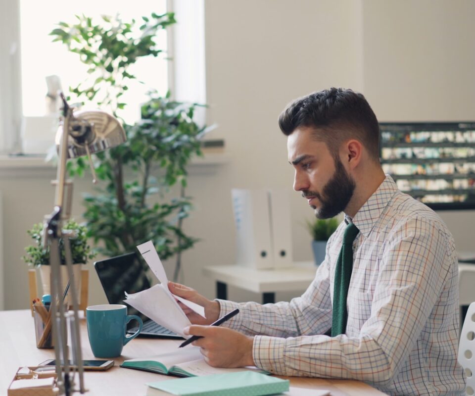 Man sitting at a desk with a laptop and papers, summarizing a long PDF report using AI