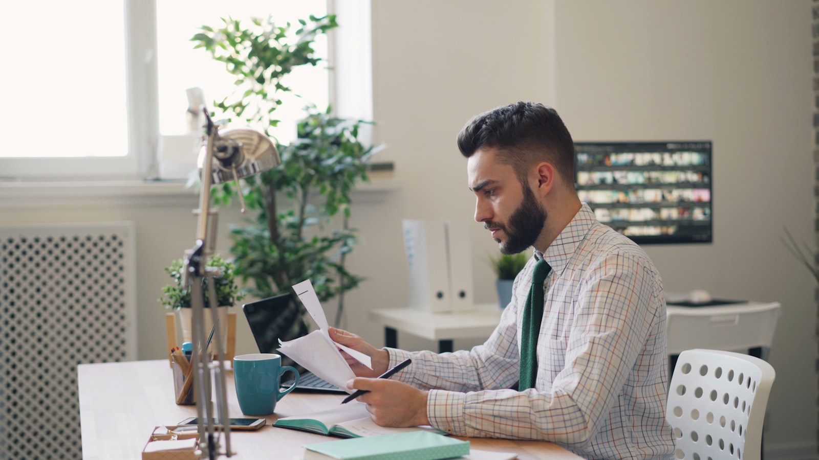 Man sitting at a desk with a laptop and papers, summarizing a long PDF report using AI